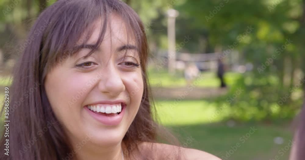 A young woman lights up as she runs to hug her friend at a park - shot on RED A young woman lights up as she runs to hug her friend at a park - shot on RED