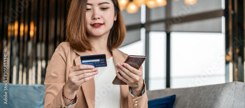Banner  web page or cover template of Asian woman using credit card with mobile phone  laptop for online shopping in modern lobby  technology money wallet and online payment concept credit card mockup