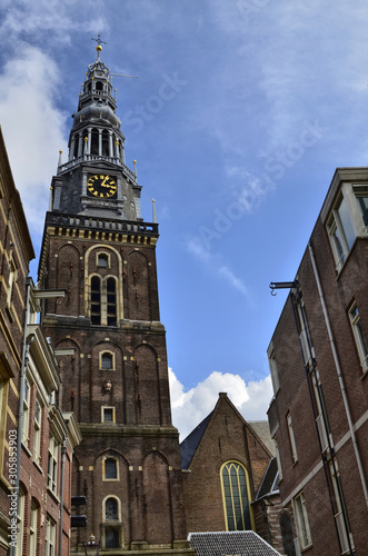 Amsterdam, Holland. August 2019. The bell tower of the old church stands out in height on the houses making itself noticed from afar.