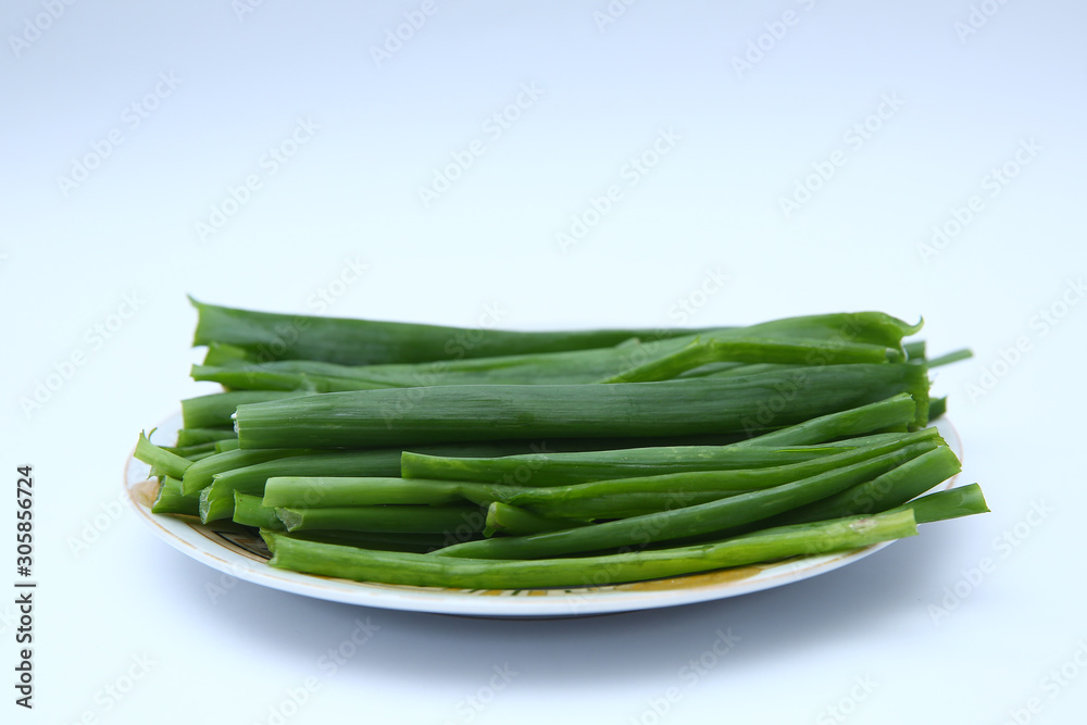 green onion on white background . onions which are green onions white plate with some smaller green onions sliced next to it on a kitchen table. green onion on white background . onions which are green onions white plate with some smaller green onions sliced next to it on a kitchen table.