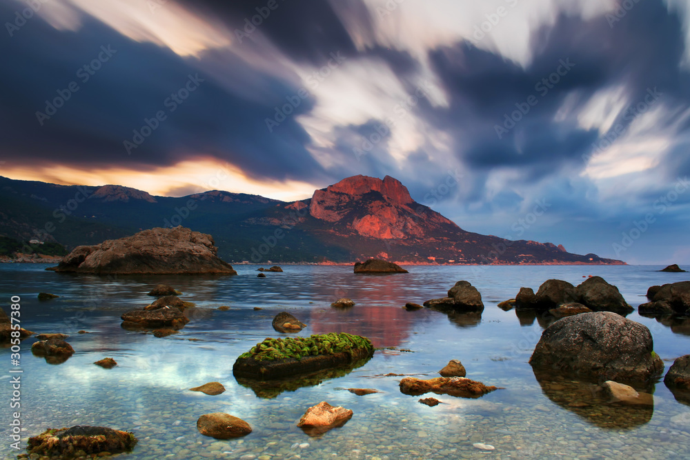 Sunset on the rocky shore of tropical sea