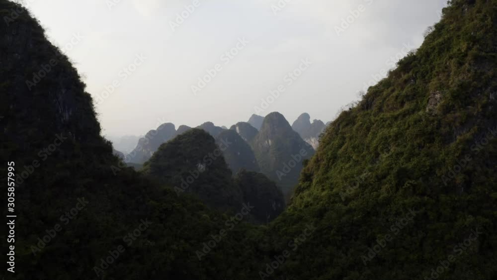 Evening dusk over karst mountain peaks at sunset, China, aerial valley reveal Evening dusk over karst mountain peaks at sunset, China, aerial valley reveal