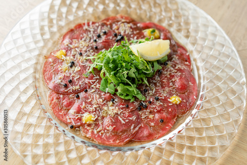Beef carpaccio with balsamic caviar and Parmesan cheese on wooden table background. Restaurant menu, natural and organic food concept.