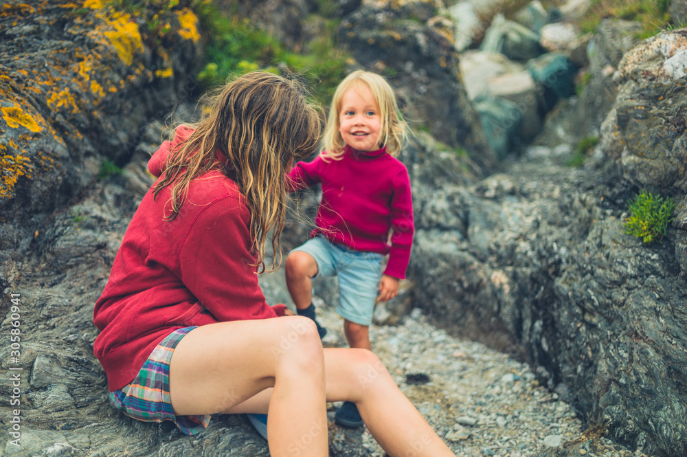 Mother helpong toddler put on shoes at the beach Mother helpong toddler put on shoes at the beach