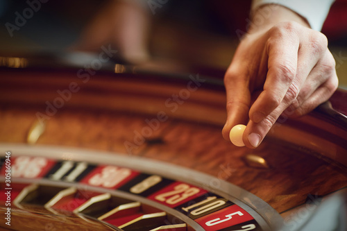 Hand of a croupier on a roulette whell in a casino.