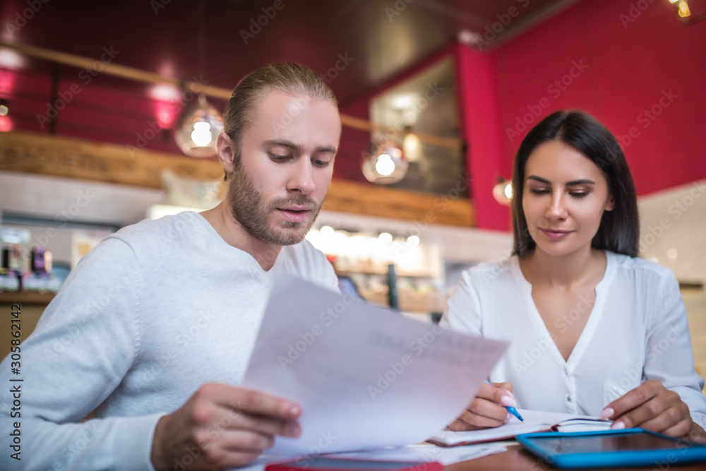 Businessman sitting near wife while making order for their cafeteria