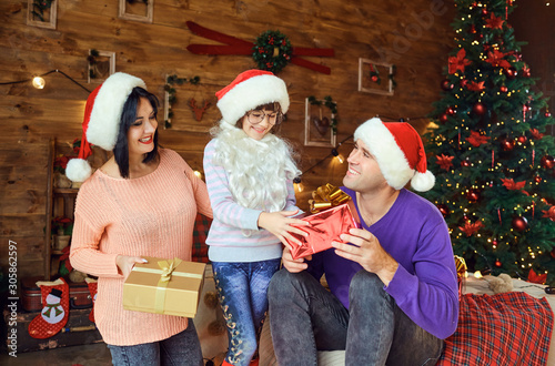 Mother and father with a child give gifts at Christmas