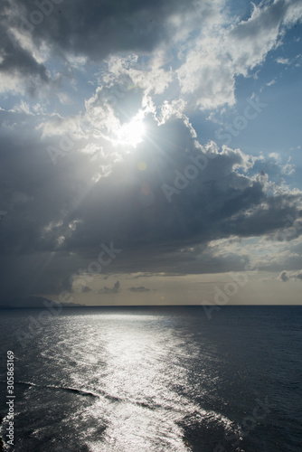 Sun light peeking through dark clouds over ocean
