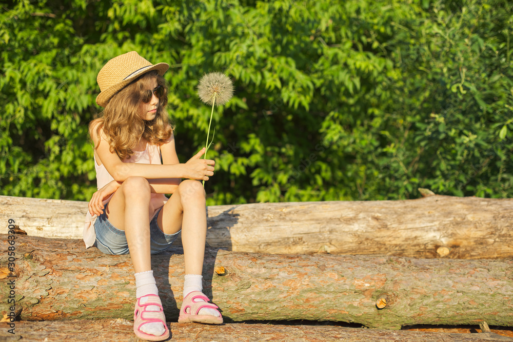 Obraz premium Summer outdoor portrait of romantic girl with big fluffy dandelion
