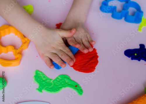 Child hands playing with colorful clay. Homemade plastiline. Girl molding modeling clay. Homemade clay. Child playing and creating from play dough. photo