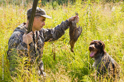 hunter takes downed grouse from a dog