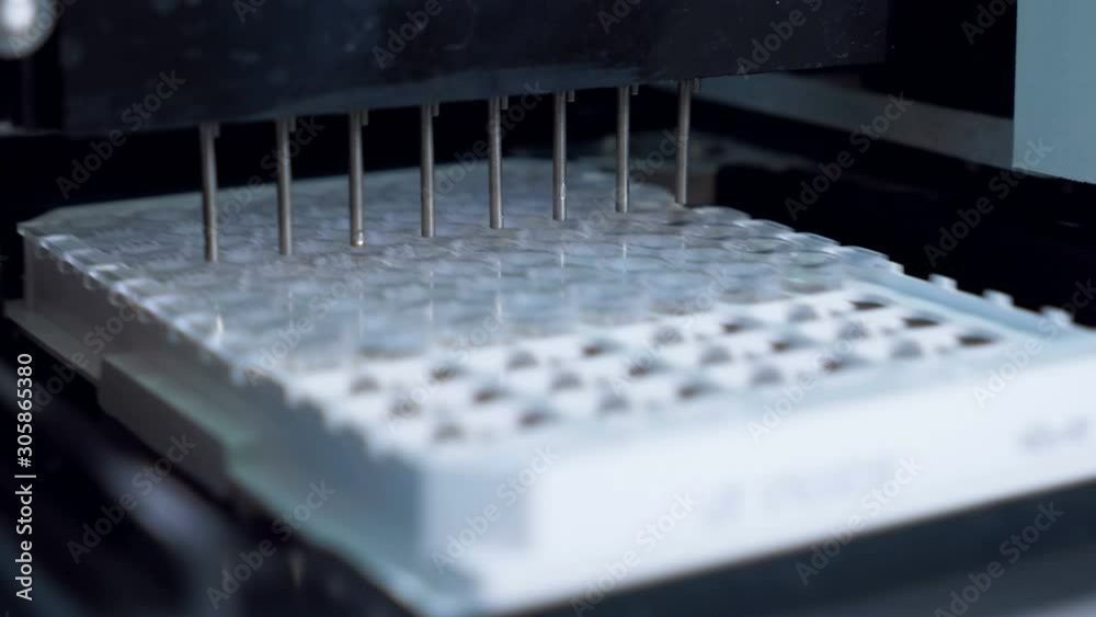 Automated machine pours liquid into tubes at a laboratory while working. Automated machine pours liquid into tubes at a laboratory while working.
