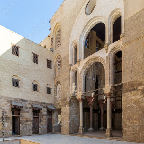 Main courtyard of public historic mosque of Sultan Qalawun with huge arches, wooden doors and decorated windows, Cairo, Egypt