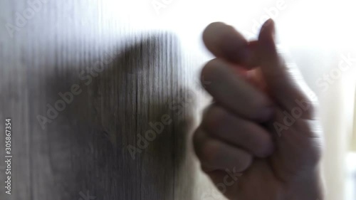 Male hand knocking at wooden door, visitor or guest at the door.