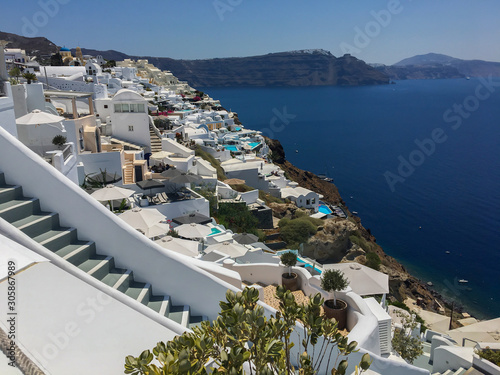 Ancient greek volcanic island from above. Roofs of houses on the mountain against the background of the sea. Flowers cactus succulents foreground.