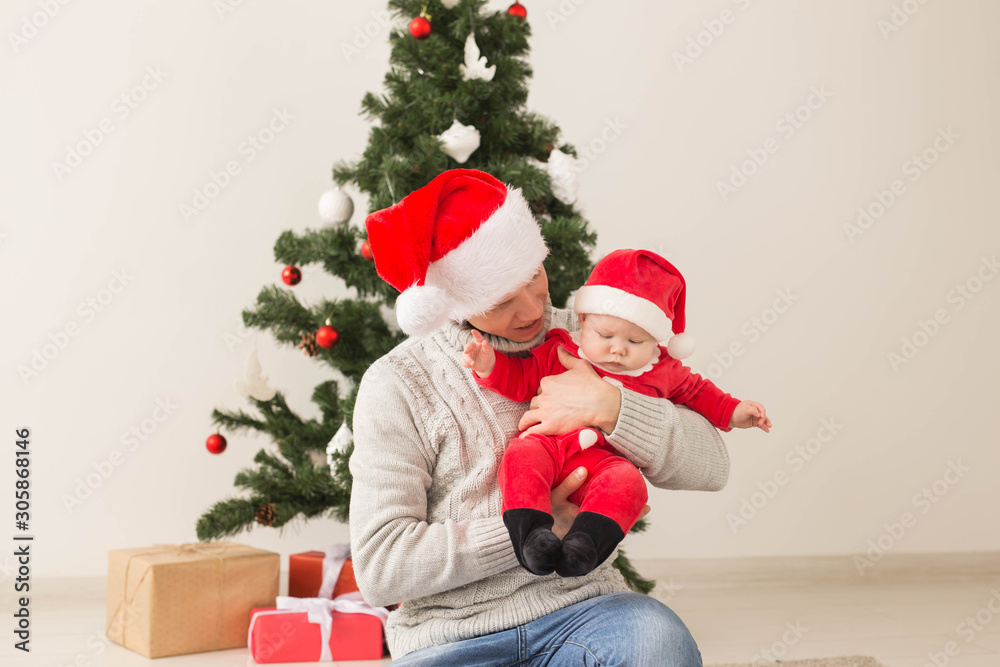Father with his baby boy wearing Santa hats celebrating Christmas. Father with his baby boy wearing Santa hats celebrating Christmas.