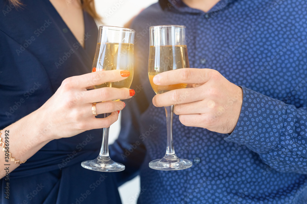 Close-up of man and woman celebrating Christmas or New Year eve party with glasses of champagne.