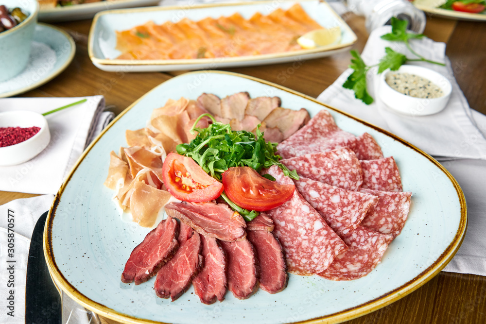 Meat plate, delicacy and Anantipasto. Salami, roast beef, Parma ham, smoked duck breast. Various snacks and antipasti on the table. Italian cuisine Restaurant menu, natural and organic food concept.