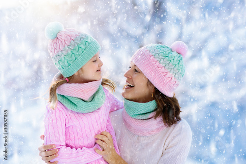 Mother and child in knitted winter hats in snow.