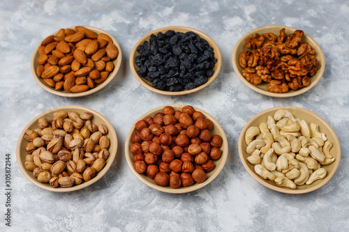 Assortment of nuts in ceramic plates. Cashew, hazelnuts, walnuts, pistachio, pecans, pine nuts, peanut, raisins.top view