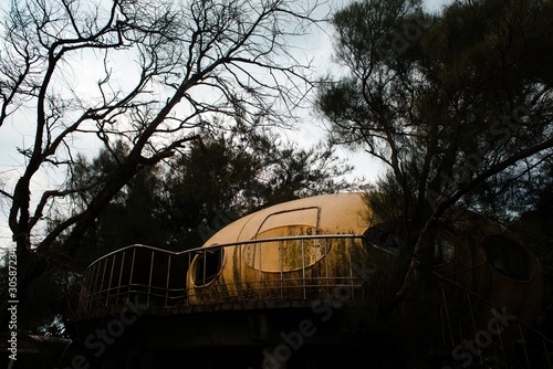 Abandoned yellow UFO house near tall trees in the evening in Wanli UFO Village, Taiwan photo