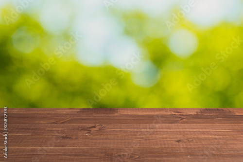 Wooden table in front of a blurred background. Perspective brown wood over blurred wooden planks background - can be used to showcase or assemble your products. Mock up to display the product.