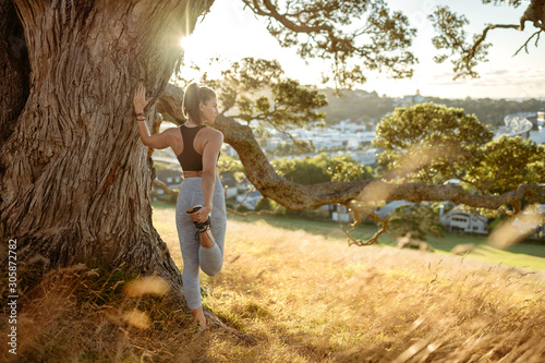 Young woman stretching under tree in park