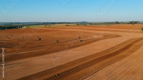 Aerial view of farmer plows with his tractor on his farm for peanuts planting in the rural areaAerial view of farmer plows with his tractor on his farm for planting in the rural area photo