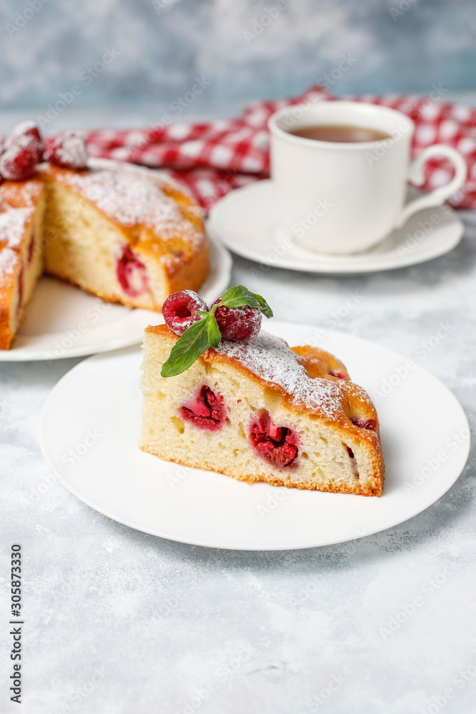 Raspberry cake with powdered sugar and fresh raspberries on a light background. Summer berry dessert. Raspberry cake with powdered sugar and fresh raspberries on a light background. Summer berry dessert.