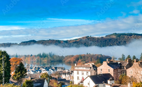 Aerial top view over Bowness On Windermere on an early morning with fog and mist rising on lake Windermere. Autumn in the Lake District, Cumbria, UK. 