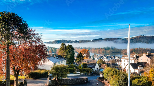 Aerial top view over Bowness On Windermere on an early morning with fog and mist rising on lake Windermere. Autumn in the Lake District, Cumbria, UK. 