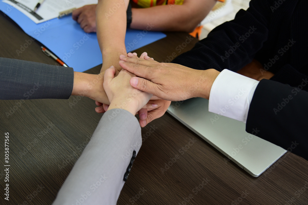 People putting their hands together. Business partners or friends with stack of hands showing unity, teamwork and cooperation.