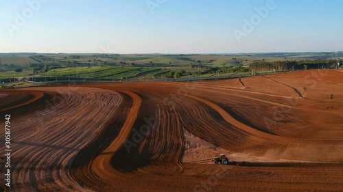 Aerial view of farmer plows with his tractor on his farm for peanuts planting in the rural areaAerial view of farmer plows with his tractor on his farm for planting in the rural area photo