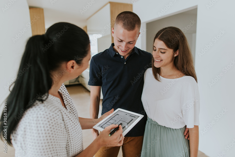 Estate agent using digital tablet showing young couple new house Estate agent using digital tablet showing young couple new house