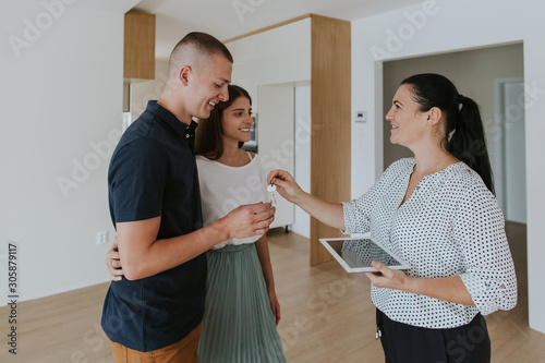 Estate agent handing keys to young couple in new house