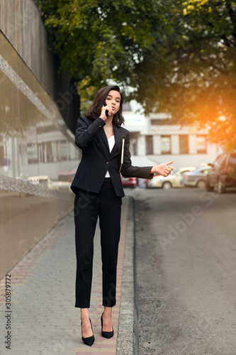Businesswoman in a city street waving for taxi