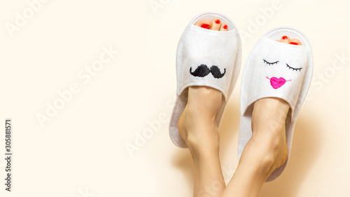 Cute funny couple. Woman with legs upwards wearing unusual slippers with faces of man and woman © Leart