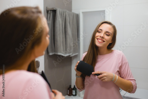 young woman brushing her hair in bathroom