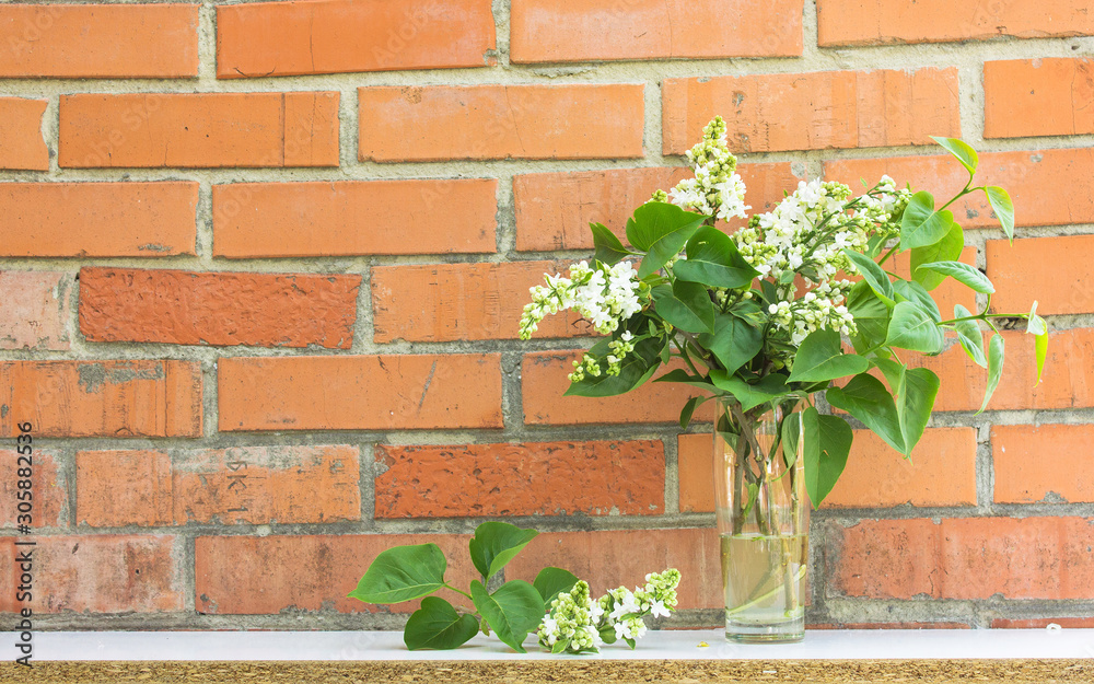 bouquet of lilac flowers in styled vase with books near exposed brick wall. Empty frame mock up for presentation design. Template framing for modern art. bouquet of lilac flowers in styled vase with books near exposed brick wall. Empty frame mock up for presentation design. Template framing for modern art.