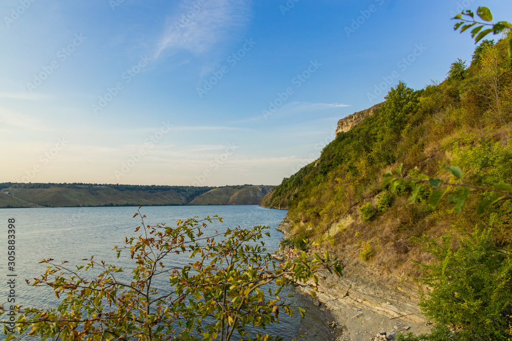 Obraz premium nature reserve green rocky hills coast line of lake silent waters scenic landscape environment morning sun rise spring time 