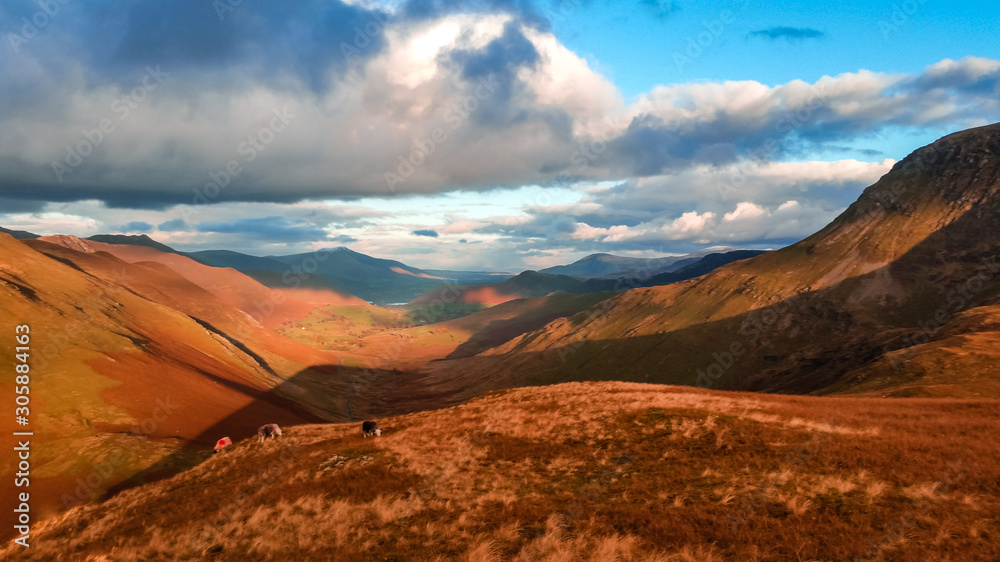 Naklejka premium Scenic valley in autumn with snow capped mountain peaks. Touristic destination in the Lake District, Cumbria, United Kingdom. Top aerial view of peaks.
