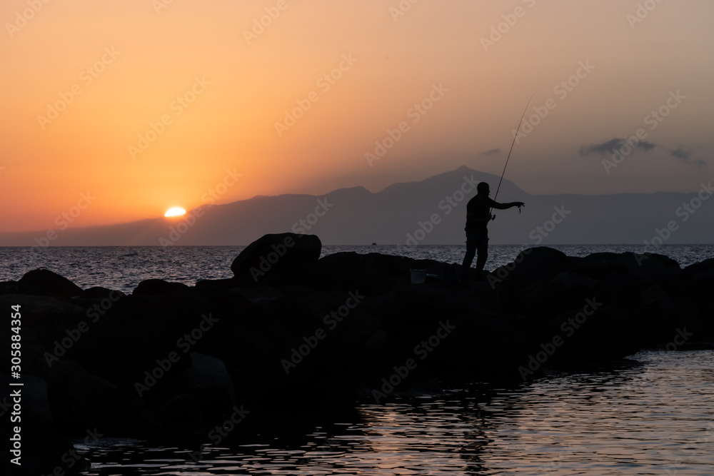 Fisherman silhouette .fishing at sunset in Gran Canaria, Canary islands, Spain. .Teide views from Gran Canaria