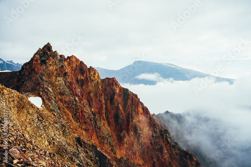 Beautiful pointed rocky pinnacle in cloudy sky. Vivid big pointy rocky peak. Giant piece of stone. Atmospheric minimalist alpine landscape. Sharp rocky mountain top in sky. Wonderful highland scenery.