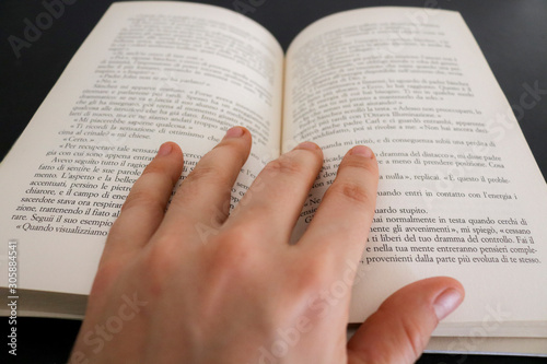 Primo piano di una mano di una donna che sfoglia le pagine di un libro, educazione e letteratura