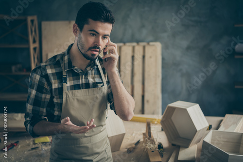 Busy worried overloaded foreman handyman speak on smartphone have problems with clients decide offers furniture construction restoration repair orders in home workplace