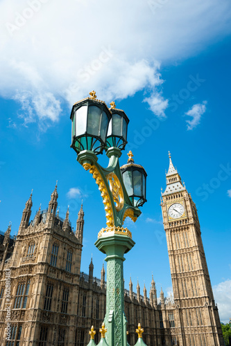 Bright blue sky scenic view of Big Ben and the Houses of Parliament with an ornate street lamp on Westminster Bridge in London, UK