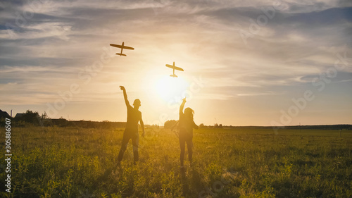 A guy and a girl launch a paralon plane at sunset.