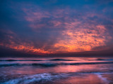 Beautiful orange dawn / sunrise over the Mediterranean Sea, waves splashing against the shore