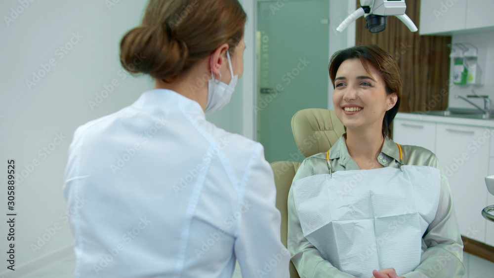 Fototapeta premium Smiling girl talks to doctor in clinic