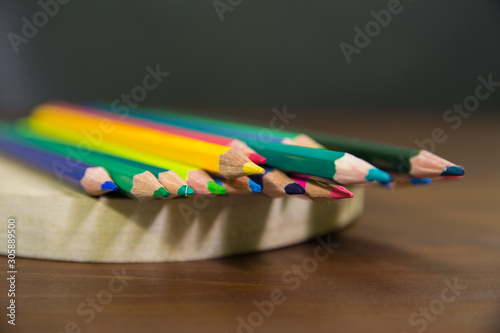 color pencils nib in focus on a wooden stand and talbe with a black backrground